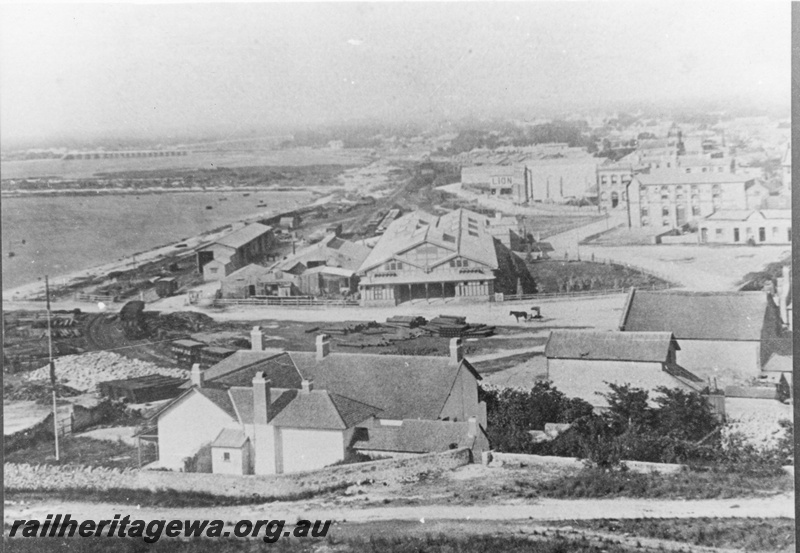 P02739
Fremantle railway station (original) looking east with old workshops on the left and goods shed. Picture taken after station roofed in 1887. Cliff St crossing in the middle of the photo. c1890.
