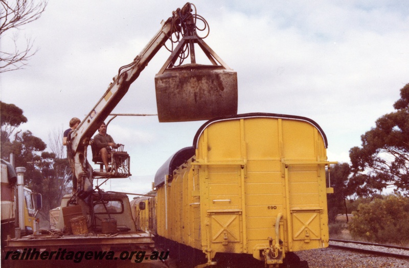 P03584
RCK class 23966, ex RCA class, with extended sides and ends with a corrugated iron sliding roof, fertilizer being unloaded by truck mounted bucket crane, end view, Moora, MR line
