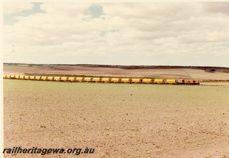 P04025
Diesel loco, Westrail orange with blue stripe, heading mineral sands train of at least 23 wagons, side view from long distance
