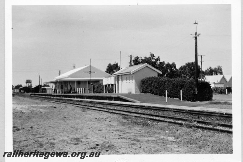 P09394
Pinjarra, station buildings, platform, nameboard, loco shed and water tower in distance, view from rail side. SWR line.
