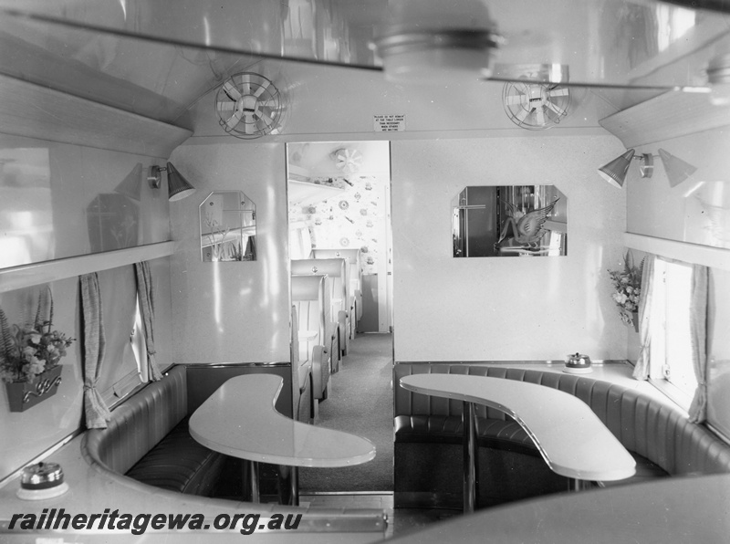 P10396
AYS class buffet car showing curved dining tables, saloon fans and portion of saloon seating. Note the wall mounted overhead lights and wall mounted mirrors.
