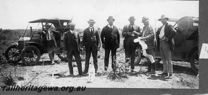 P16828
Commonwealth Railways (CR) - TAR line officials standing in front of motor cars at the opening of the railway near Ooldea.
