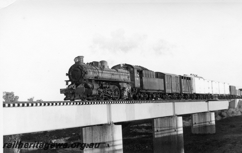 P17759
PMR class 734 steam locomotive with 42 Goods travelling to Perth. SWR line. Location possibly the Roelands bridge. Side view of locomotive and train.
