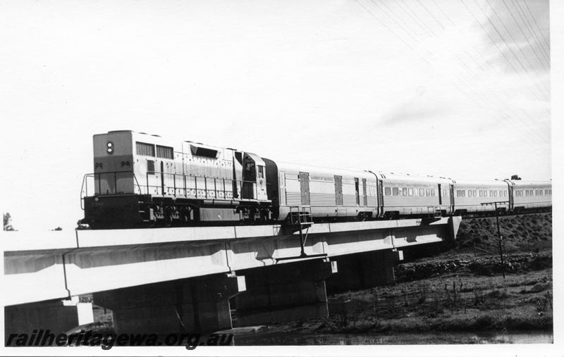 P17771
L class 268 diesel locomotive hauling the empty set of the Trans Australian to Forrestfield and crossing the bridge at Woodbridge. ER line.3/4 side view of locomotive and leading carriages. Note the concrete bridge and pylons, also safety places on side.
