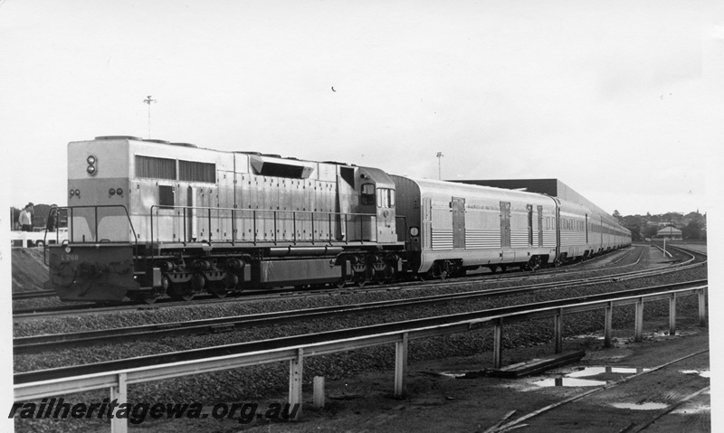 P17772
L class 268 diesel locomotive with the inaugural standard gauge passenger train at East Perth Terminal. ER line. Trackage in foreground, behind safety fence, is the narrow gauge suburban line to Midland. Trackage on lower right is remains of East Perth locomotive depot tracks. Side view of locomotive .
