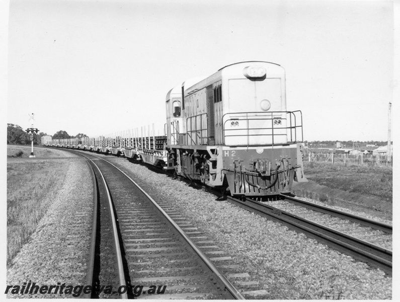 P17866
H class 2 standard gauge diesel locomotive with a rake of wagons loaded with welded rail enroute to Merredin. The train is seen near Upper Swan.
