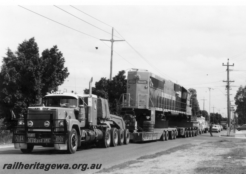 P18117
2 of 4 Hamersley Iron 6062 class diesel locomotive being road hauled from Kewdale to Dampier. Note road traffic behind load.
