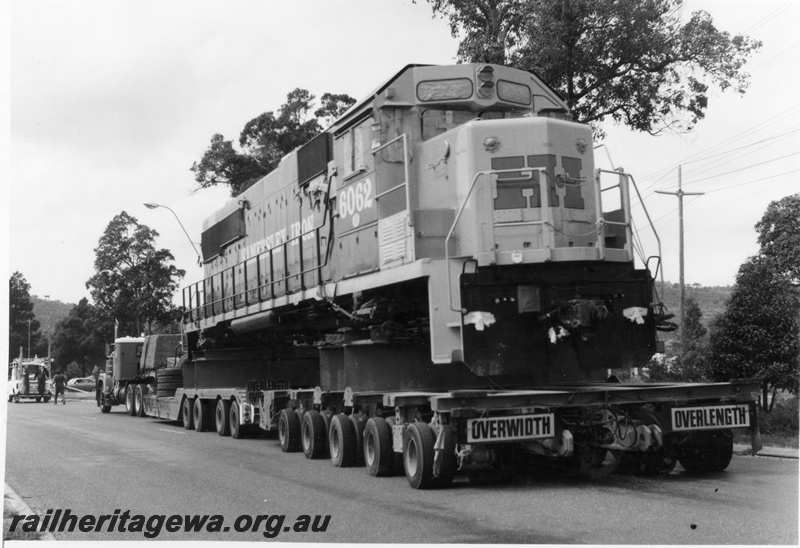 P18119
4 of 4 Hamersley Iron 6062 class diesel locomotive being road hauled from Kewdale to Dampier. View of cab front of locomotive.
