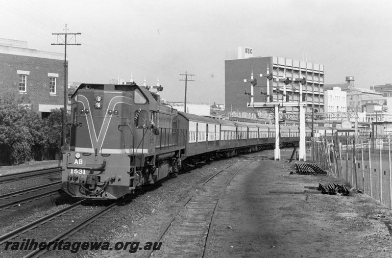 P18129
AB class 1531 diesel locomotive hauling a special service departing Perth to Midland. ER line. Front view of locomotive. Semaphore signals to right of train as is former Road Coach depot.
