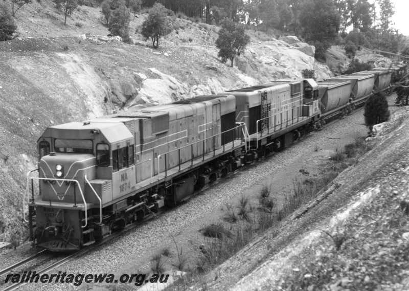 P18138
NA class 1874 diesel locomotive and an unidentified locomotive hauling an empty bauxite train to Mundijong.
