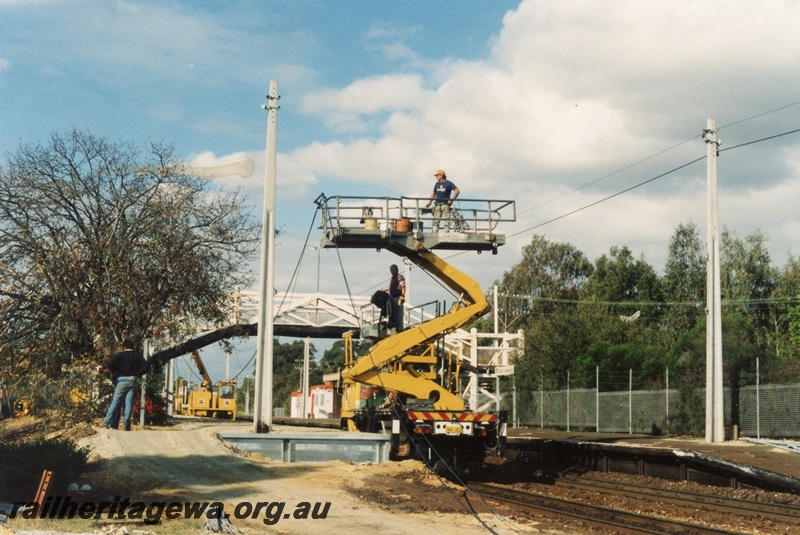 P18309
Cherry picker wagon and workmen, erecting overhead power cables, overhead footbridge, West Leederville station, ER line
