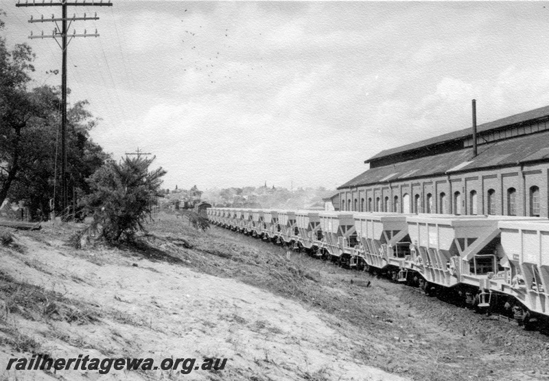 P18343
2 of 4, Rake of WMC class hoppers, beside the loco shed, East Perth loco depot, telegraph poles on the right hand side of track
