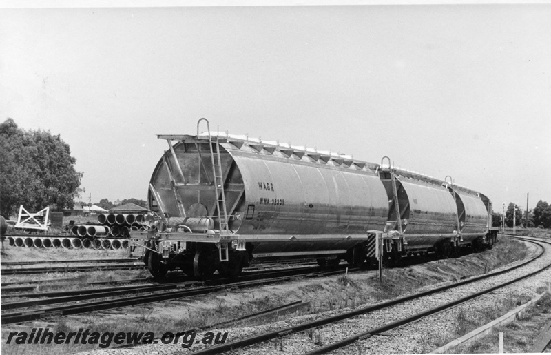 P18524
WWA class 32301, and two other WWA class wagons with the wheat sheaf motif on the sides, being shunted by J class 102, signals, end and side view
