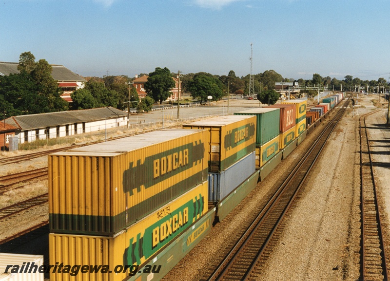 P18659
Midland and portion of a westbound freight train, pictured from the overhead footbridge, travelling to Forrestfield/Kewdale. Double stacked containers, 48' foot in length, included in the load. ER line.
