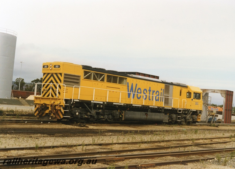 P18665
Q class 303 standard gauge diesel locomotive pictured at Forrestfield adjacent to portion of the carriage washing plant.
