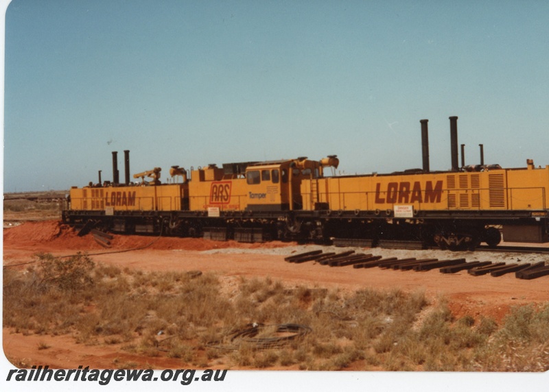 P18726
Loram rail grinder, used by BHP, sleepers beside track, Port Hedland, side and end view
