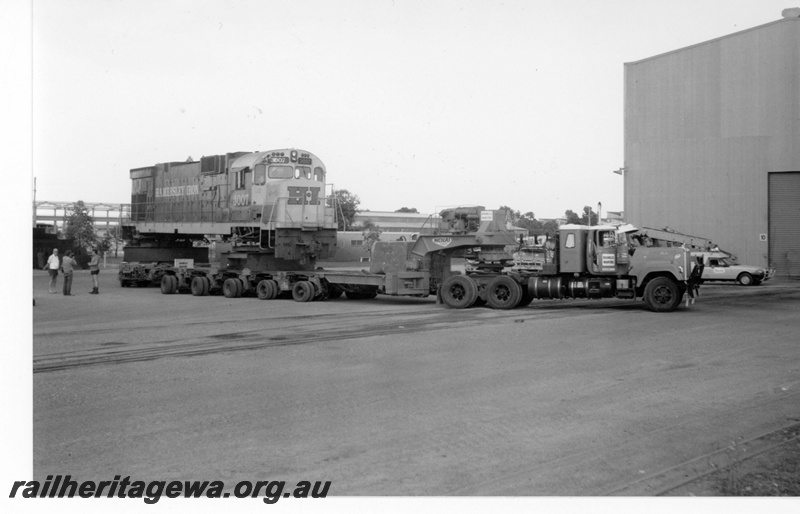 P18801
Hamersley Iron (HI) C636 class 3007 on low loader in Comeng's works Bassendean for rebuilding. Side view of prime mover and low loader.
