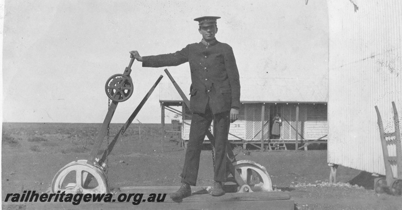 P19020
Point levers, station building, hand trolley, Thomas French in uniform, tent home number 36, woman in doorway, TAR line 
