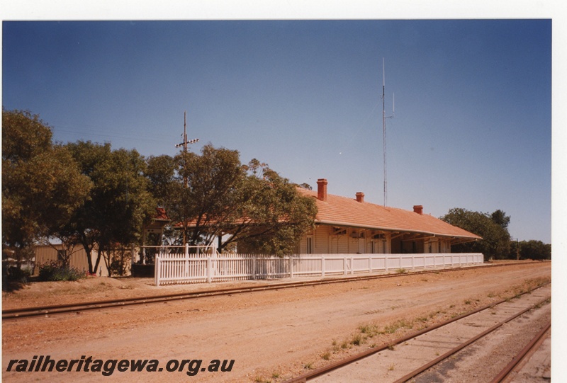 P19115
Station building, Wyalkatchem, GM line. White picket fence between the building and the railway line, end and trackside view.
