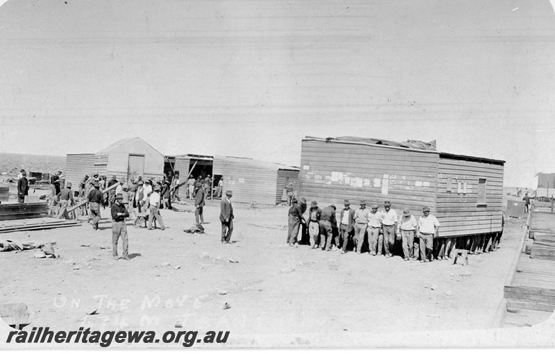 P19170
Commonwealth Railways (CR) construction camp being shifted, workers lifting wooden house and carrying timber, 474 mile, TAR line
