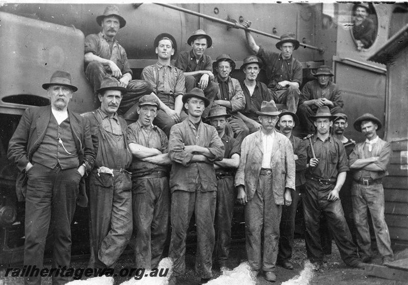 P19172
Group photo of Commonwealth Railways (CR) workers, standing in front of and largely obscuring G class 10, TAR line, track level view
