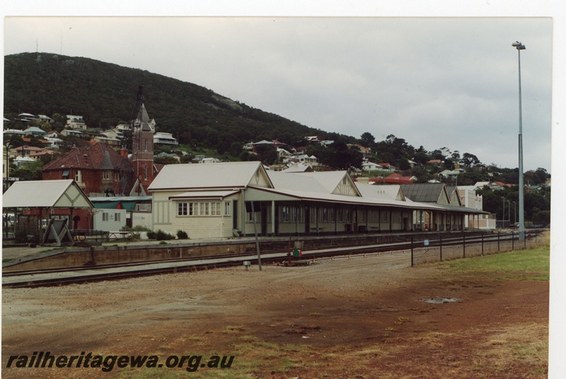 P19242
Station building, platform, tracks, clock tower, hill and part town in the background, Albany, GSR line, track level view
