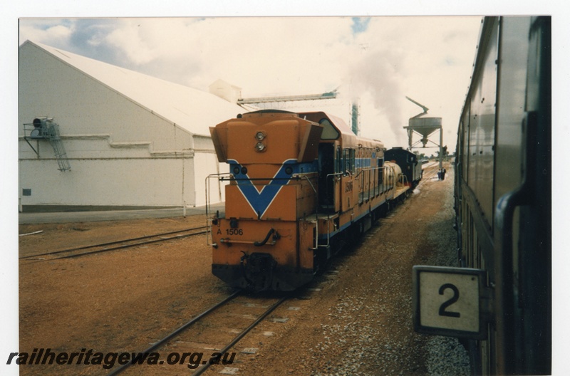 P19246
A class 1506, in orange livery with blue and white stripe, tanker wagon, steam tank loco, wheat bin, loading facility, passenger carriage no 2, end and side view from adjacent carriage
