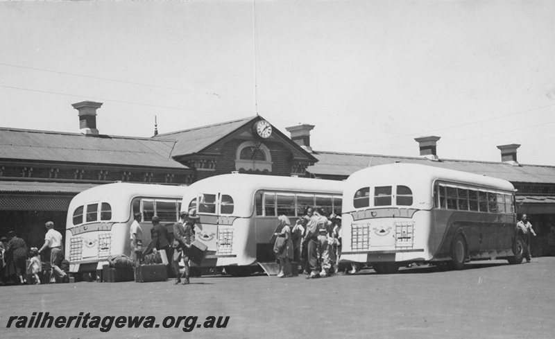 P19645
Railway Road Service buses parked in the forecourt of the Bunbury Station, passengers around the buses, end and side view

