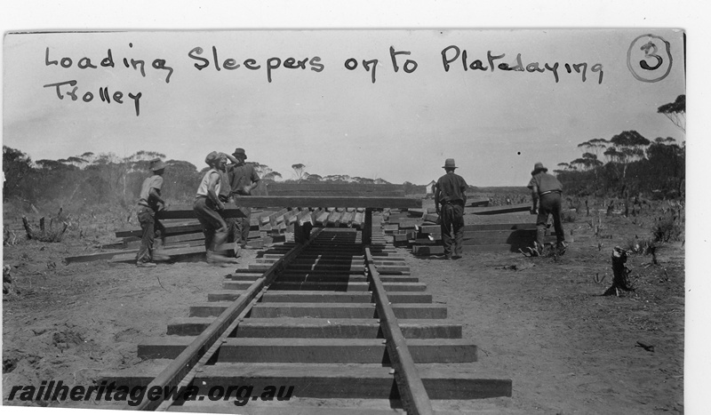P19662
Loading sleepers on to plate laying trolley. Location unknown.
