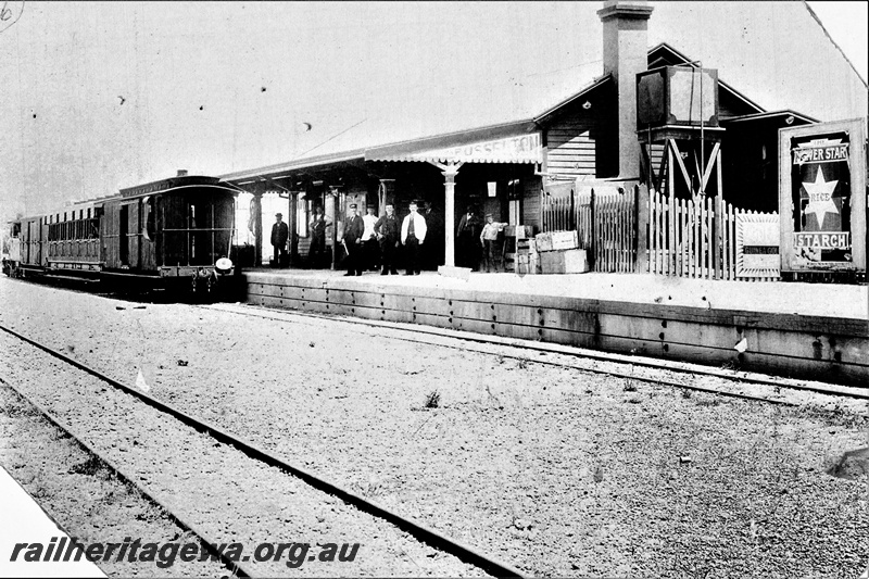 P19704
Station building, station name on the end of the station platform canopy, people on the platform, end platform brakevan with a clerestory roof on the train at the platform, Busselton, BB line, end and trackside view of the building
