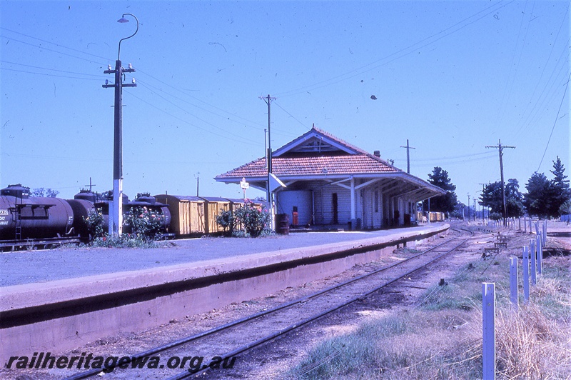 P19826
Station building, platform, station nameboard, rake of vans and tanker wagons, track, rodding, Tambellup, TO line
