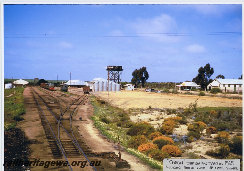 P20042
Station and yard, station building, points, sidings, X class loco in green livery with red and yellow stripe, on goods train, wheat bins, water tower, buildings, point lever, Caron, MR line, view form up home signal looking south

