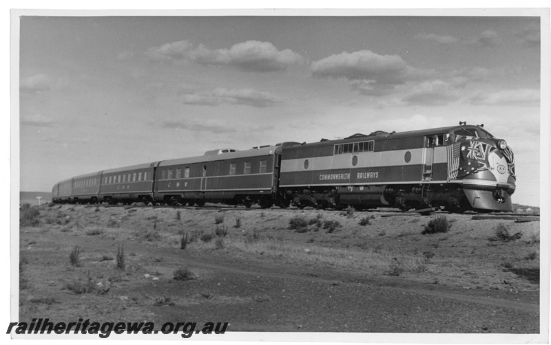 P20123
Commonwealth Railways (CR) GM class diesel, with nose festooned with national flags, on the new Trans-Australian train consisting of Wegmann carriages, inaugural run, TAR line, side and front view
