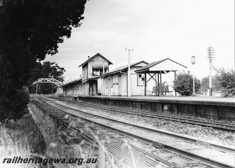 P20697
Station buildings, signal box, overhead footbridge, platform, station nameboard, shelter, seats, rodding, tracks, Chidlow, ER line, view from track level
