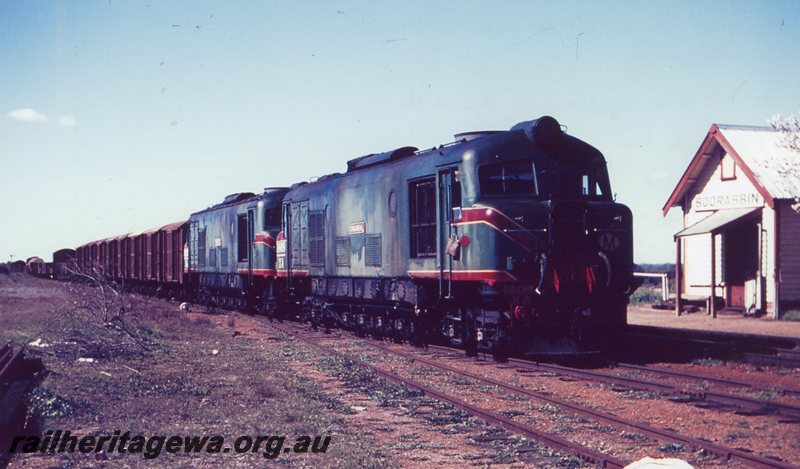 P20751
XA class 1409 and unidentified XA  (both locomotives green with red/yellow stripe livery) arrive Boorabbin from Kalgoorlie with a goods train. Station building and Up home signal in photo. EGR line.

