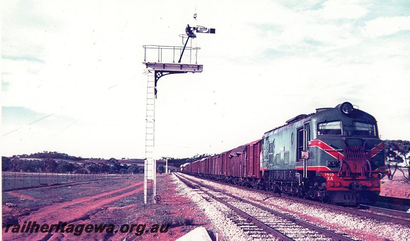 P20761
XA class 1415 (green with red/yellow stripe livery) approaches East Northam from Merredin with load of wheat. The railway on the left is the Goomalling branch. Home and distant signal in photo.  EGR line. 
