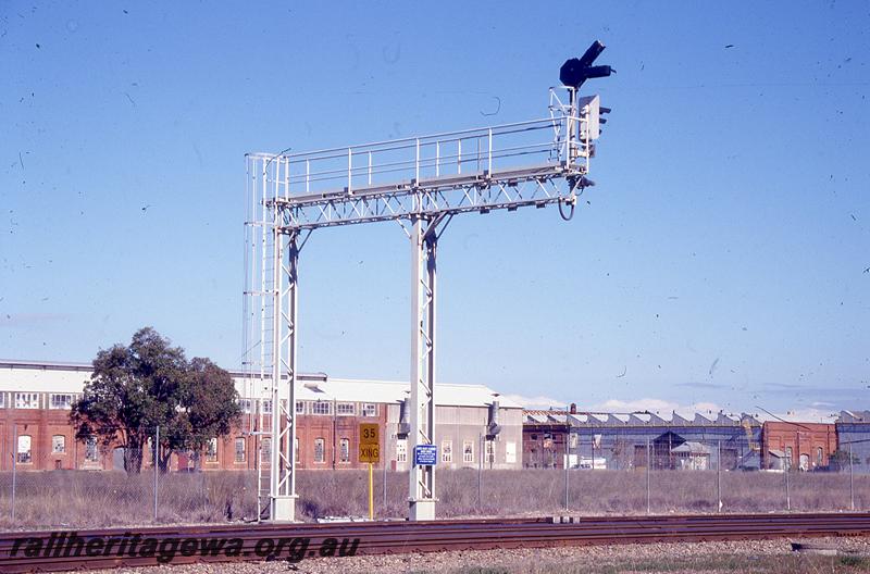 P21042
Steel lattice signal gantry with colour light signals, Midland, the Midland Workshops in the background
