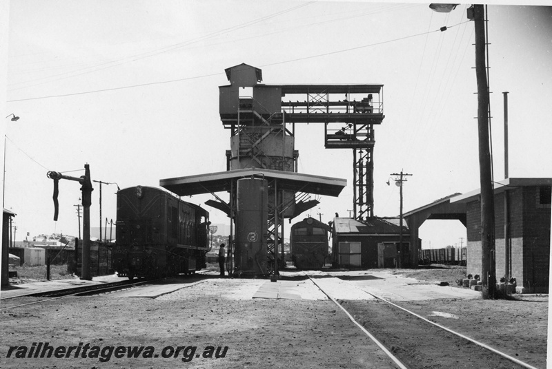 P21174
R class 1902, X class 1013, water column, diesel fuel point, sheds, former coal stage in background, Bunbury loco depot, SWR line, front on view, c1970s
