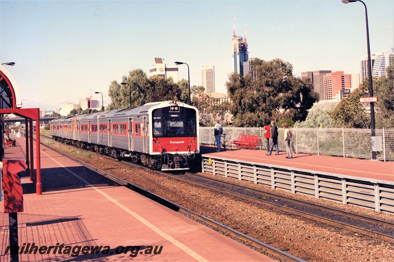 P21302
Transperth ADL class 809 heading a four railcar set, red and black front,  entering West Perth station, passengers on platforms, city background, ER line, side and front view (see also P20686)
