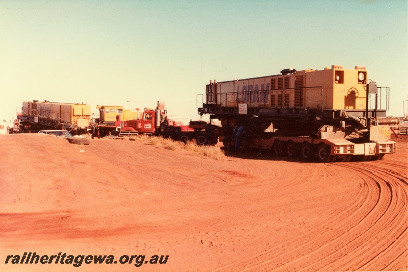 P21320
Loram Australian Rail Service rail grinder, the three component units on individual road trucks, red soil, Port Hedland, ground level view
