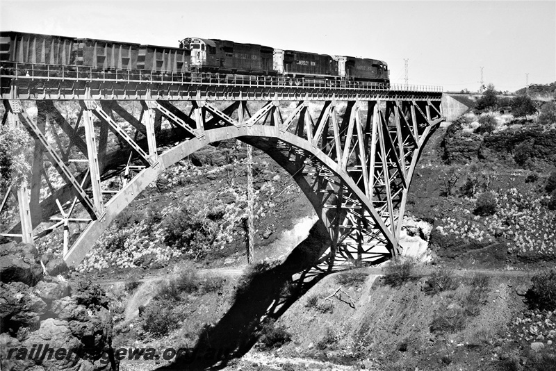 P22204
Three Hamersley Iron diesels numbered 3009, 2004 and 4049, triple heading an ore train, crossing steel arch bridge, Pilbara, rear and side view
