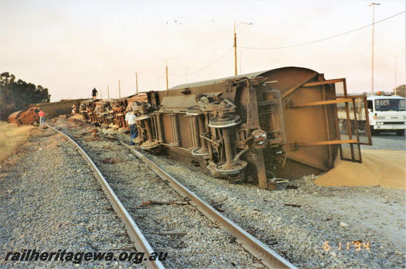P22845
Derailment of XWA class grain wagons at Forrestfield 1 of 2, wagons lying off track and on their sides, truck, workers, view from trackside along the derailed train
