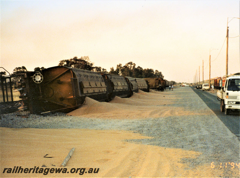 P22846
Derailment of XWA class grain wagons at Forrestfield 2 of 2, wagons lying off track and on their sides with grain spilt on ground, truck, onlooker, view from roadside along the derailed train
