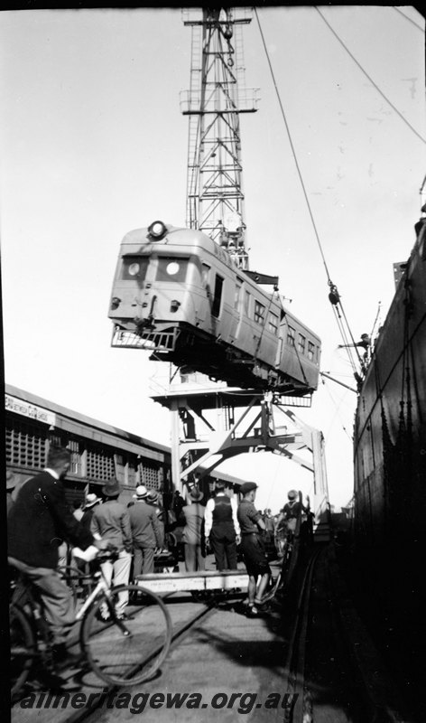 P22902
Governor Stirling railcar, without wheels, being unloaded by port crane, onlookers, warehouse, side of ship, Fremantle, ER line, view from wharf
