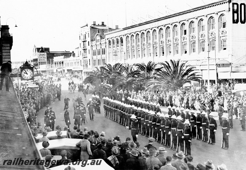 P22925
Arrival of Governor, soldiers on parade, crowd of onlookers, Boans department store, station clock on front of station building, Wellington Street, Perth station, ER line, view from elevated position
