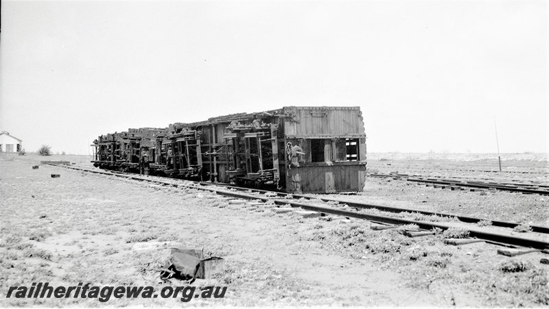 P22937
Aftermath of floods at Port Hedland PM line in January 1939 3 of 3, vans on sides beside rails, house, track level view
