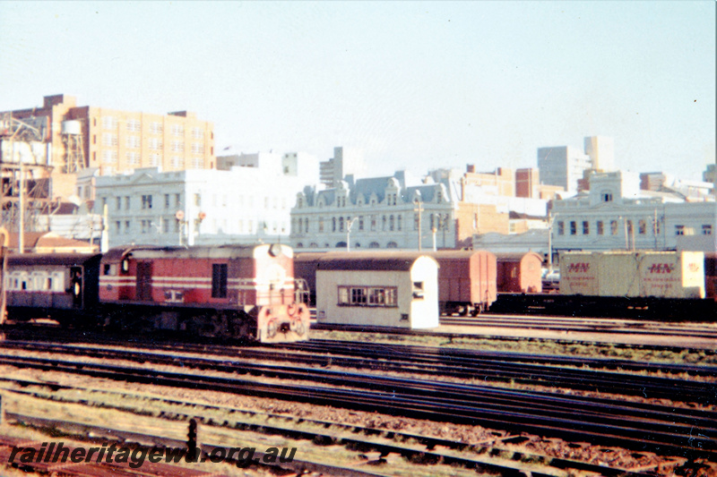 P23035
Diesel loco in Midland Railway Co livery on passenger train, vans, trackside building, city buildings in background, Perth goods yard, ER line, side and front view
