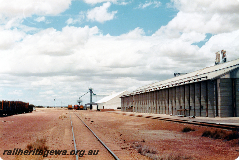 P23065
Locomotive, wagons in distance, wheat bins, overhead loader, conveyor, track, Wialki, KBR line, track level view
