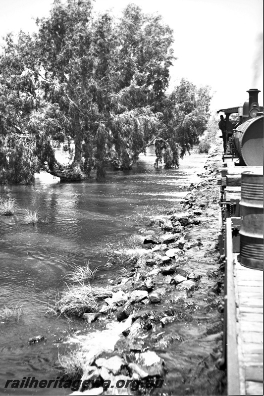 P23163
2 of 3 views of the Port Hedland floods, PM line,  H class 8802  wagon with drums being hauled by a G class loco, view along the train.  
