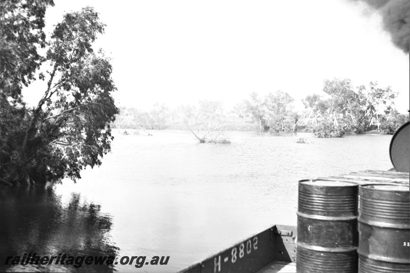 P23164
3 of 3 views of the Port Hedland floods, PM line ,  H class 8802  wagon with drums being hauled by a G class loco, view along the train. 
